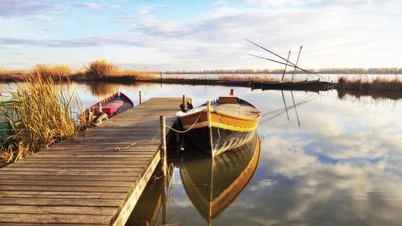 Laguna de la Albufera en Valencia con embarcadero y barca reflejada en el agua al amanecer