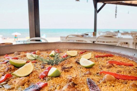 Paella frente al mar en restaurante con terraza y vistas al océano, ideal para disfrutar de cocina mediterránea.